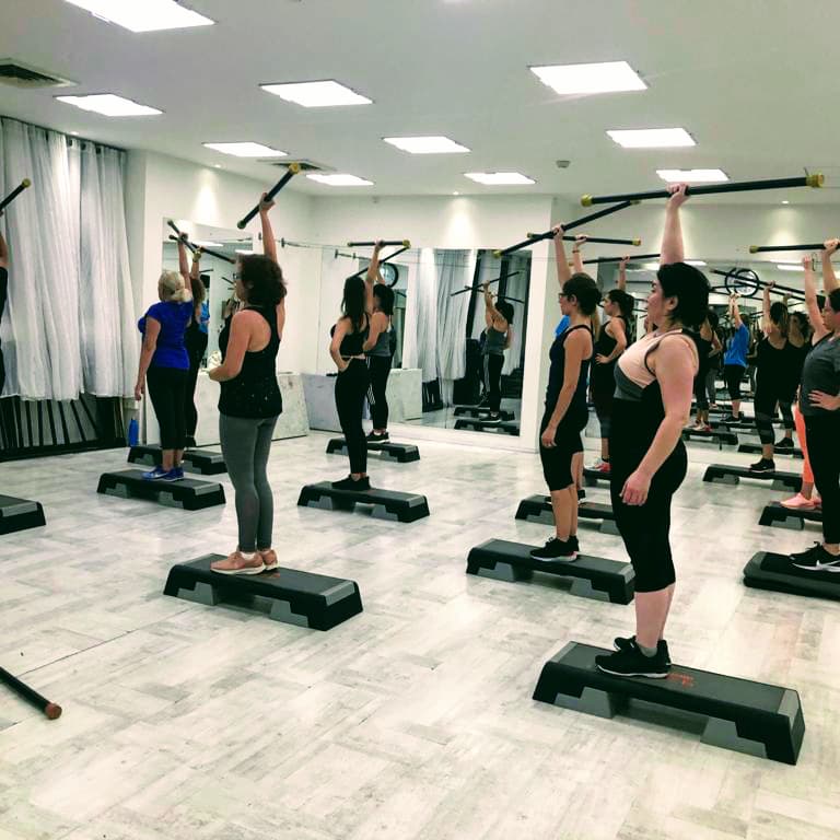 נשים מתאמנות יחד עם מקלות ומדרגות בתוך הסטודיו